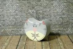 a cat shaped vase sitting on top of a wooden floor next to a brick wall