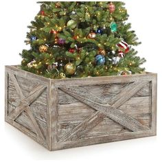 a christmas tree in a wooden box with ornaments on it's sides and a white background