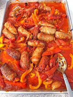 a pan filled with sausage and peppers on top of a table