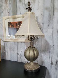 a lamp sitting on top of a black table next to a framed photo and a painting