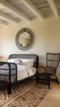 a bed room with a neatly made bed and a mirror on the wall above it