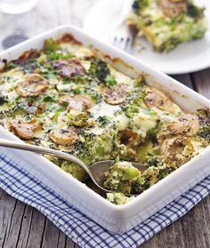 a casserole dish with broccoli and mushrooms in it on a wooden table