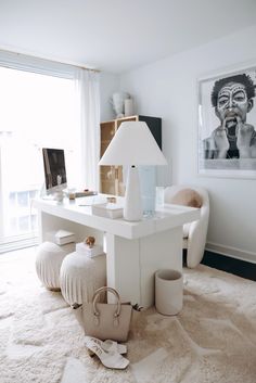 a white desk in the corner of a room with pictures on the wall behind it