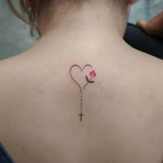 the back of a woman's neck with a cross and rose tattoo on it