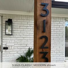 a house number sign on the side of a white brick building with black letters and numbers