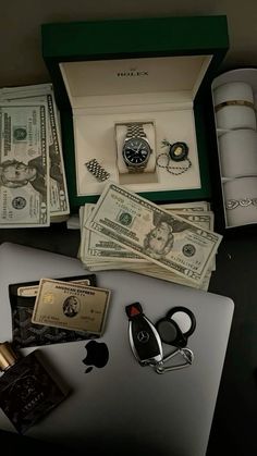 an apple laptop computer sitting on top of a table covered in money and other items