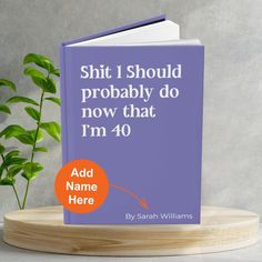 a purple book sitting on top of a wooden stand next to a potted plant