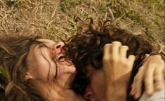 two people laying on the ground with their heads close to each other and one person touching his face