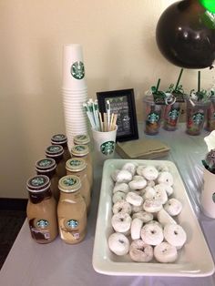 a table topped with lots of donuts and starbucks coffee cups on top of it