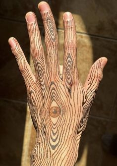 a person's hand with tattoos on it that looks like a tree trunk and has an eye in the middle