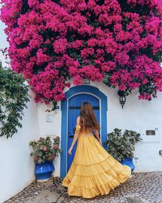 a woman standing in front of a blue and white door with pink flowers on it