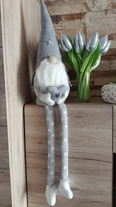 a stuffed gnome sitting on top of a wooden shelf next to a potted plant