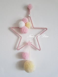 a pink and white star with pom - poms hanging from it's side