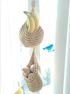 two hanging baskets filled with bananas on top of a window sill next to a blue bird