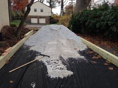 a flatbed covered in black tarp next to a house with trees and bushes