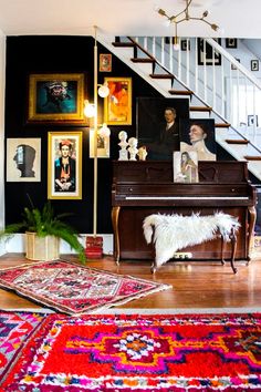 a living room filled with furniture and pictures on the wall next to a stair case