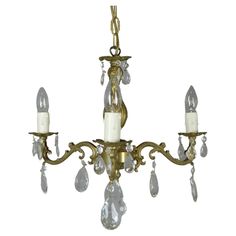 an antique chandelier with crystal drops hanging from it's arms and two candle holders