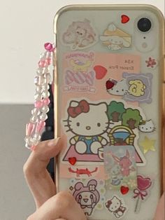 someone holding up their cell phone with hello kitty stickers on the back and side