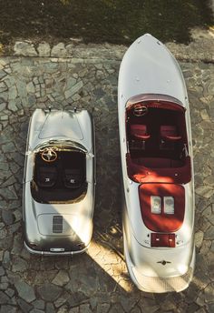 two cars parked next to each other on top of a cobblestone floored area