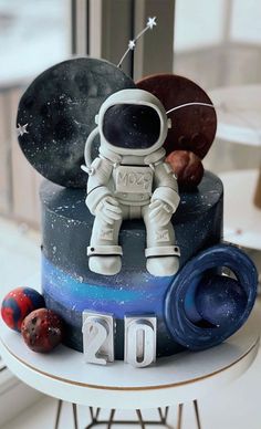 a cake with an astronaut sitting on top of it, surrounded by space related items