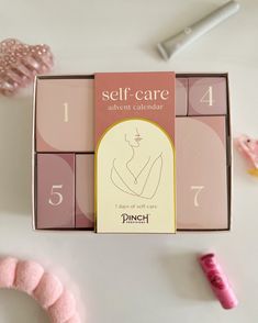 a pink box with the words self care written on it next to some fake items