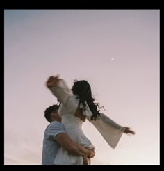 a man carrying a woman in his arms as they fly through the air at sunset