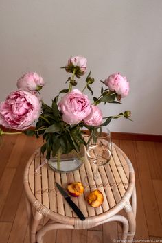 some pink flowers are in a glass vase on a table with scissors and a knife