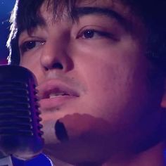 a close up of a person holding a microphone in front of a blue background with lights