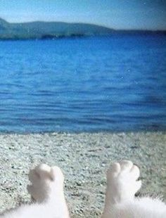 a person laying on the beach with their feet in the sand and water behind them