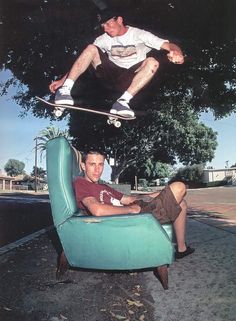 a skateboarder is jumping over a blue chair