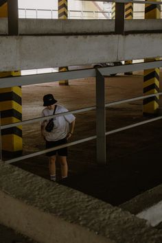 a person standing in an empty parking lot with their back to the camera and wearing a baseball cap