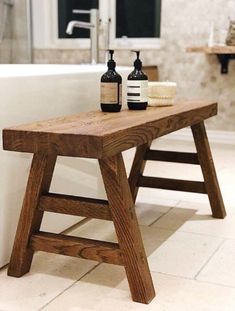 a wooden bench sitting in front of a bath tub next to a bottle of soap