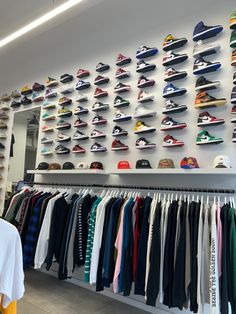 there are many shoes hanging on the wall in this store that is filled with shirts