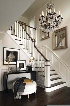 a white staircase with chandelier and pictures on the wall in front of it