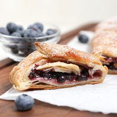 two pastries with blueberries and powdered sugar sit on top of napkins