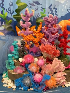 an arrangement of colorful seaweed and corals on display in front of a backdrop