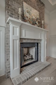 a fireplace in a living room with brick and white paint on the mantle, surrounded by two candles