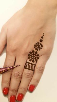 a woman's hand with henna on it and a brush in the foreground