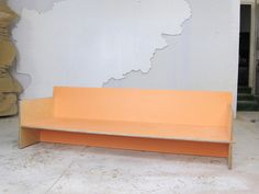 an orange bench sitting in front of a white wall and some boxes on the floor