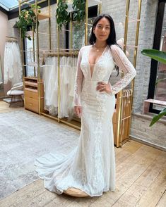 a woman in a white wedding dress standing next to a rack with dresses on it