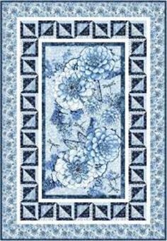 a blue and white quilt with flowers on the border, in front of a black background