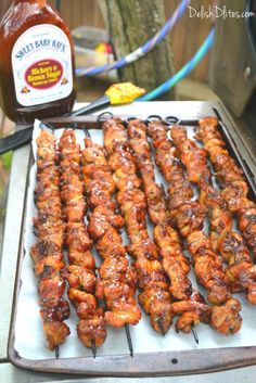 bbq chicken skewers on a grill with barbecue sauce next to it and a bottle of ketchup