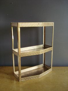 a metal shelf sitting on top of a wooden table next to a gray painted wall