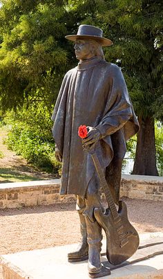 a statue of a man with a guitar in his hand and a rose on his hip