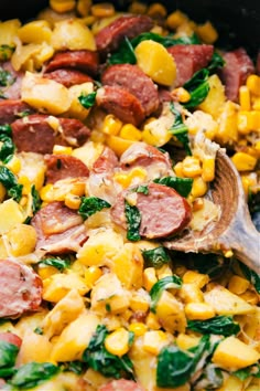 corn, sausage and spinach salad with a wooden spoon in the bowl is ready to be eaten