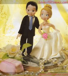 a bride and groom figurine standing next to each other in front of flowers