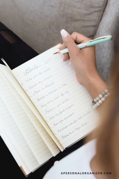 a woman holding a pen and writing on a notepad with notes in front of her