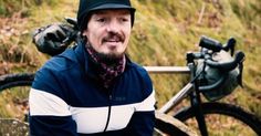 a man sitting on a bench next to a bike in the grass with other bikes behind him