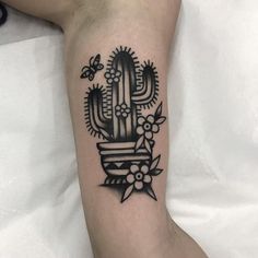 a black and white tattoo on the leg of a person with a cactus in it