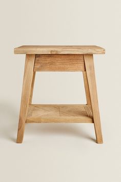 a small wooden table sitting on top of a white wall